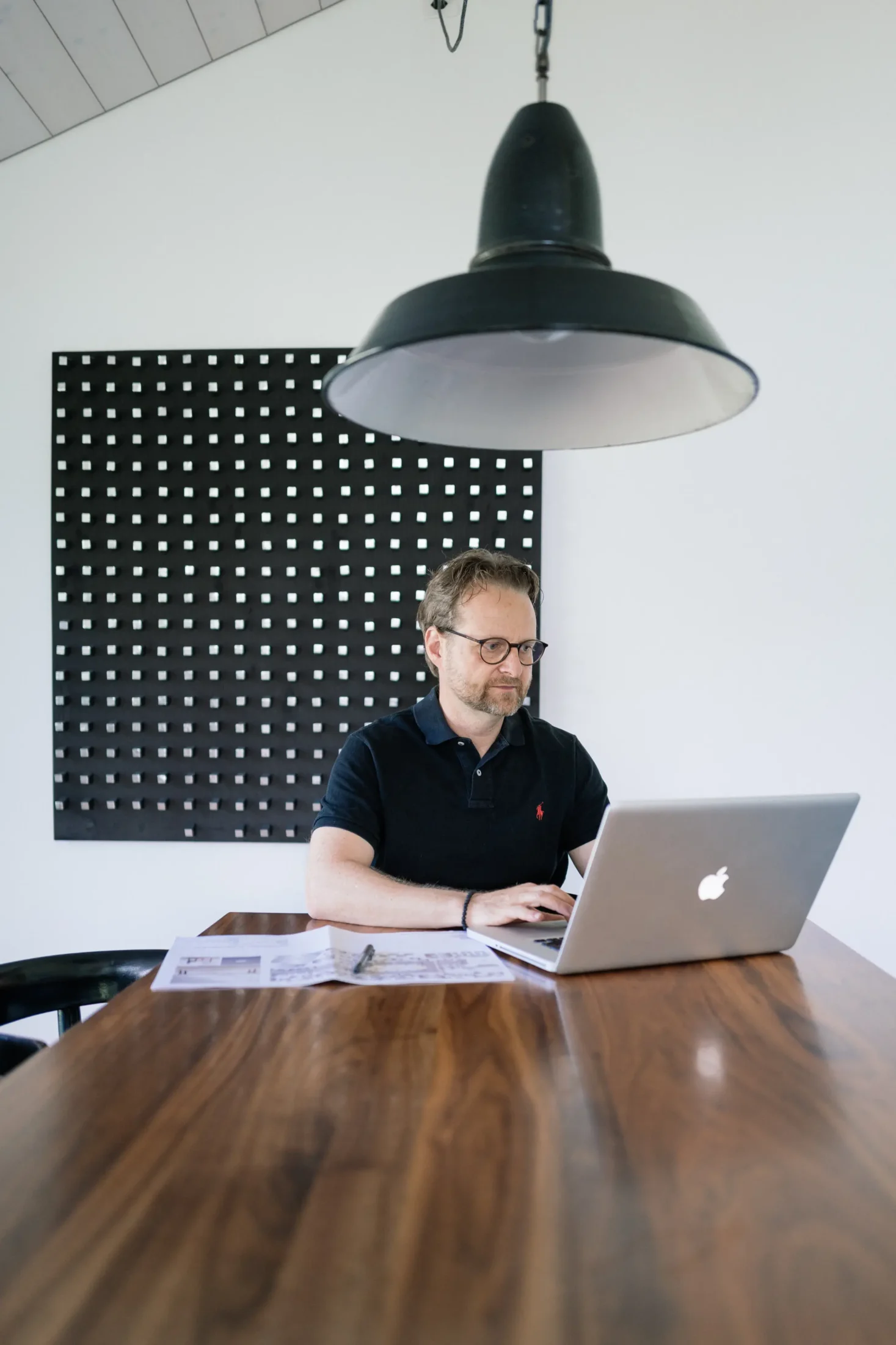 Landschaftsarchitekt arbeitet am Laptop in modernem Büro mit schwarzer Wand.